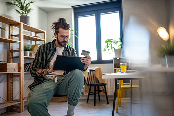 istock Young man making online payment using tablet and credit card at home 2230726394