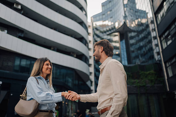 istock Businesspeople shaking hands in front of modern buildings 2230730843