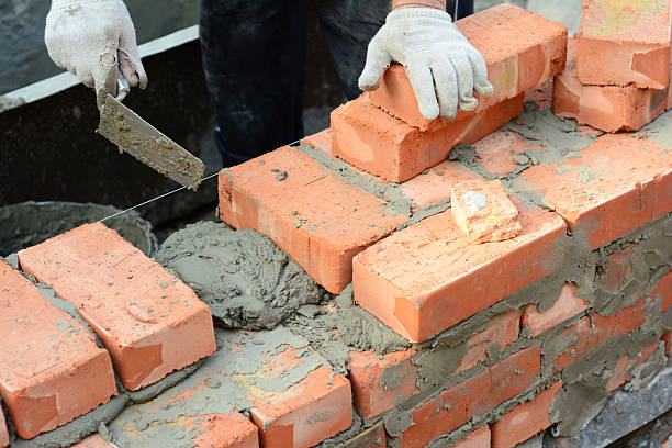 istock Bricklaying techniques. Builder building a brick wall with bricklaying trowel, bricks, concrete. 2230737254