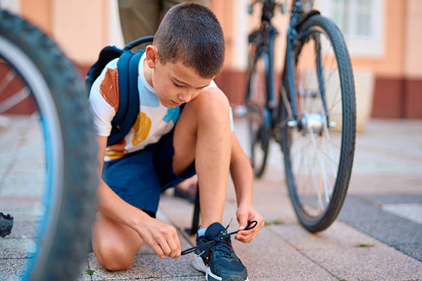 istock Schoolboy tying shoelaces next to his bicycle 2230739462