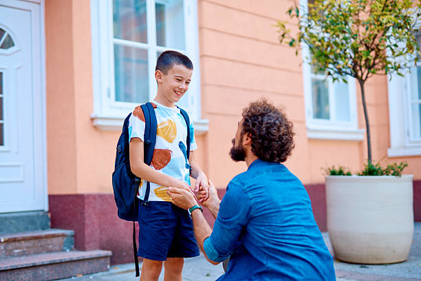 istock Father Kneeling and Holding Hands with Son Before School 2230739550