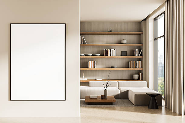 istock Modern living room interior with empty poster mockup on wall and cozy reading area with bookshelves, sofa, and coffee table near large window. 3D Rendering 2230746175