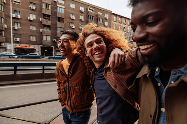 istock Three young men laughing and walking in the city 2230754031
