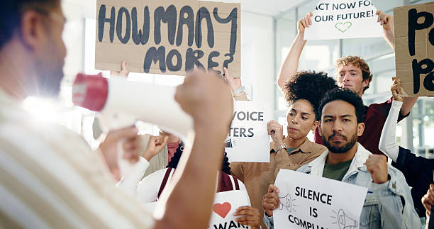 istock Megaphone, protest and group with poster, human rights or awareness for social justice or community. Revolution, people and loudspeaker for announcement of ethics, attention or demonstration or rally 2230757787