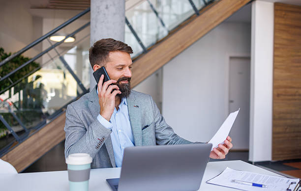 istock Businessman talking on phone and reading documents in office 2230758950