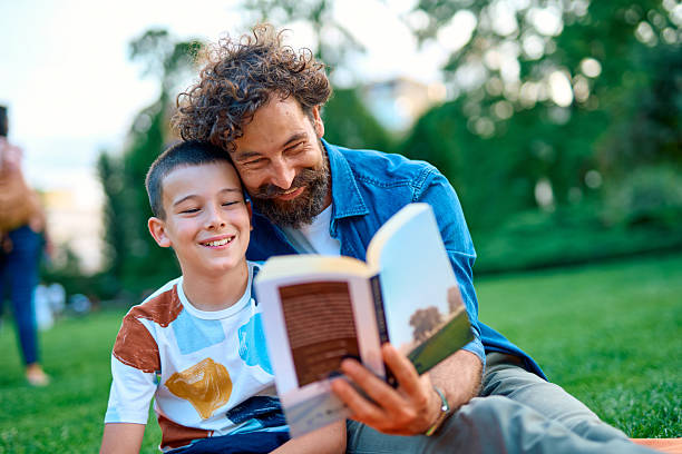 istock Father and son enjoying reading a book together in the park 2230759541
