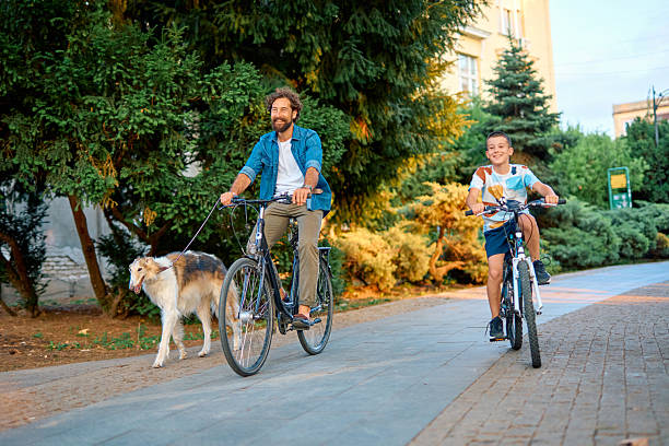 istock Father and son riding bicycles with their dog in a park 2230759633