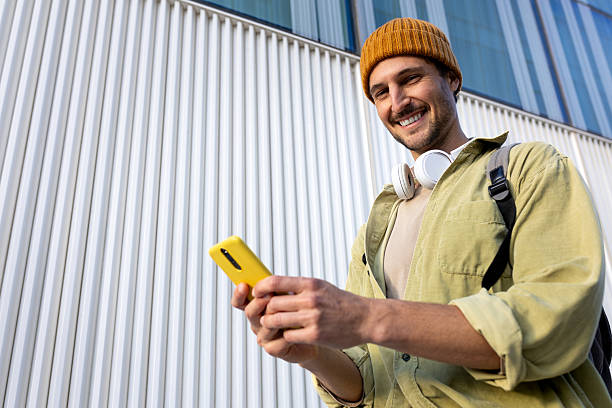 istock Smiling young man using smartphone in front of modern building 2230762104