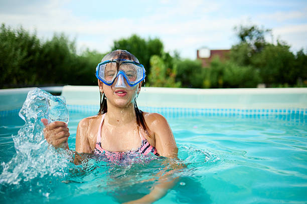 Girl blowing air through her nose while diving in a pool. She wears a blue goggle for water protection.
