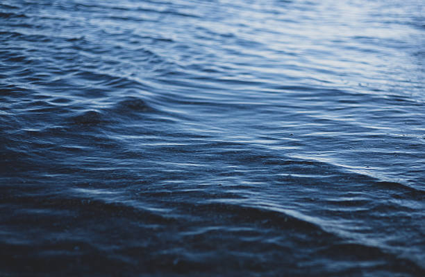 istock Blue water with ripples on the surface. Defocus blurred transparent blue colored clear calm water surface texture with splashes and bubbles. 2230767369