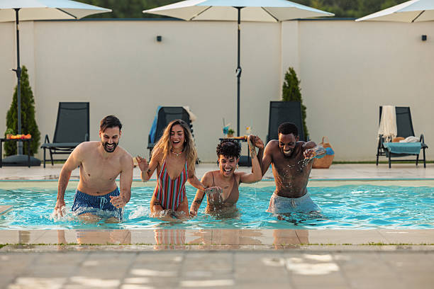 istock Four friends running and having fun in a swimming pool 2230770191