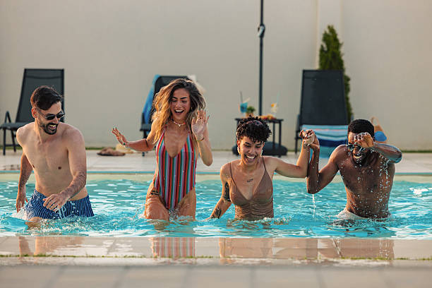 istock Friends running and laughing in swimming pool during summer vacation 2230770509