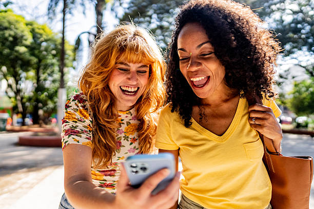 istock Friends women talking and using mobile phone outdoors 2230770662