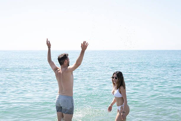 istock Couple enjoying splashing in ocean on summer vacation 2230775246