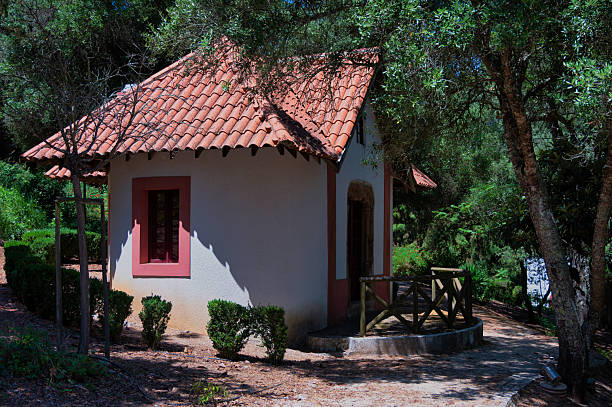 Small house with tiled roof and red window frame in the park of Santiago do Cacem, Alentejo, Portugal.
