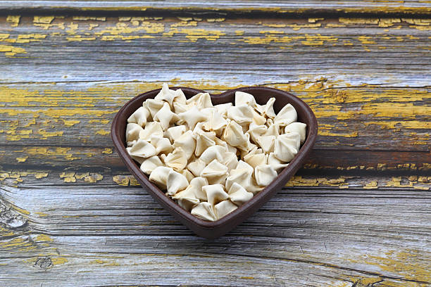 istock handmade manti (turkish ravioli type dumplings) on wooden heart shape bowl, before cooking 2230778393