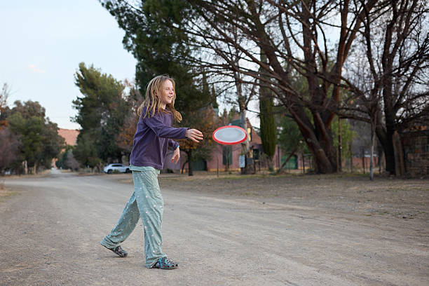 Young girl throws a frisbee to her brother. They are showing a happy lifestyle being active