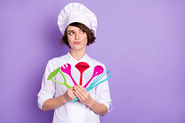 istock Portrait of attractive bewildered girl chef holding kitchenware overthinking copy space isolated over bright violet purple color background 2230778548