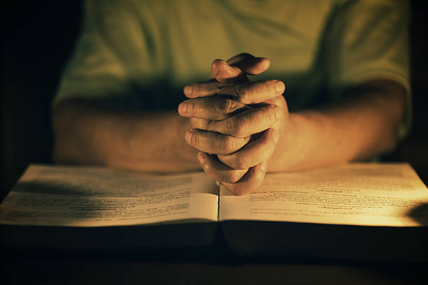 istock Praying Hands on Top of the Bible at night time. 2230778568