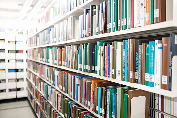 istock Rows or organized books stacked on bookshelves inside the library. Wide angle, diminishing perspective, shallow depth of field, blurry background, no people 2230778632