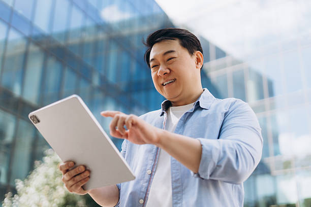 istock Asian businessman using digital tablet in front of modern office building 2230779604