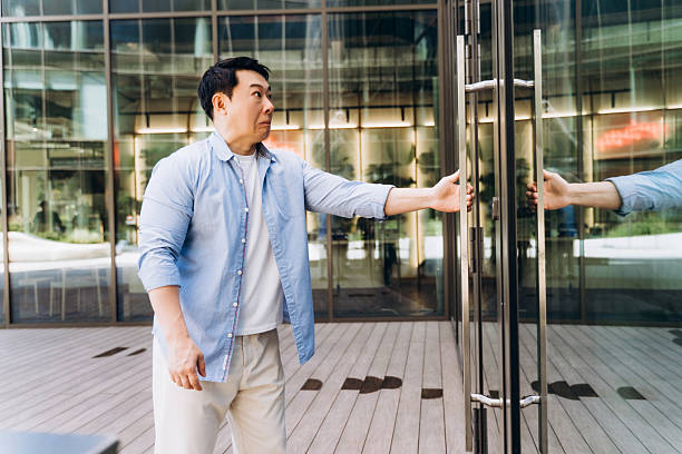 istock Asian businessman opening glass door while exiting modern office building 2230779649