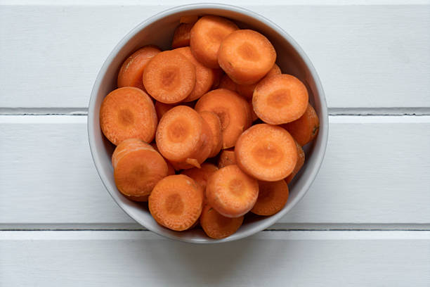 Sliced carrots in a bowl on wooden background