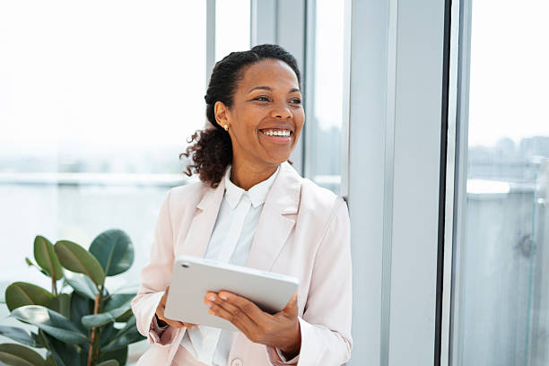 istock Smiling professional woman using a tablet indoors near large windows 2230780815