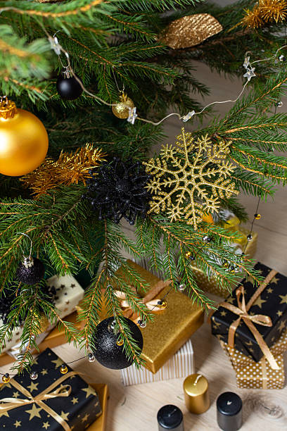 istock Luxurious gold and black gift boxes arranged beneath a Christmas tree, illuminated by glowing candles and adorned with elegant decorations, creating a chic holiday ambiance 2230781386