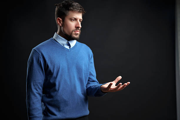 Mid adult businessman having a discussion during video call and looking at camera.