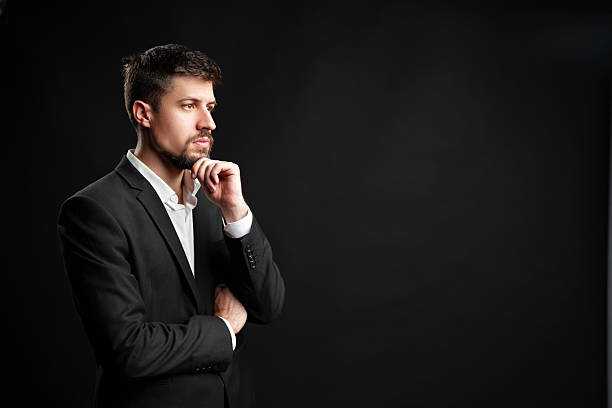 istock Professional man in a suit contemplating deep thoughts against a dark background 2230781605