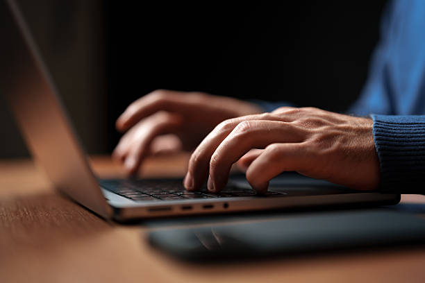 istock Hands typing on a laptop in a dimly lit workspace during evening hours 2230781634