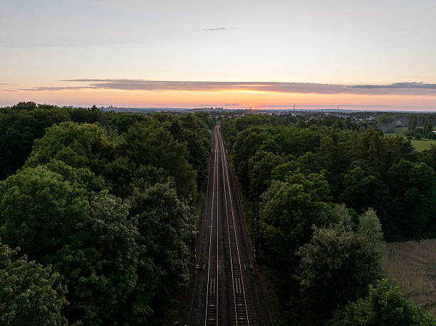 The sun sets over railway tracks disappearing into a forest near Prague, Czechia