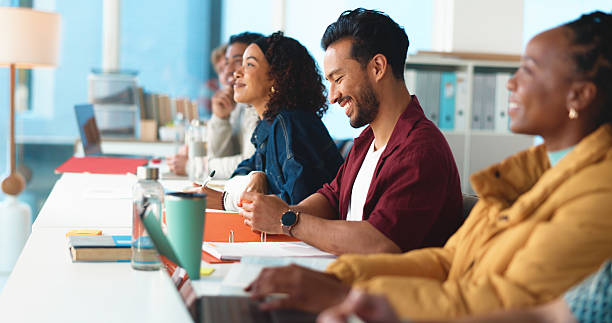 istock University, man and students in classroom, smile and learning with project. Happy people, men and women with education, college and academy with development, scholarship and assignment with joke 2230782743