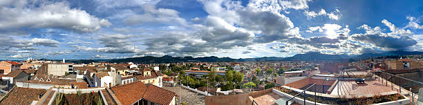 Panoramic view of Cuenca, Azuay, Ecuador, featuring the city's rooftops, the Andes Mountains, and a cloudy sky creating a picturesque urban landscape
