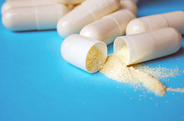 istock White pills, open capsules with powder on blue background, close-up 2230784648