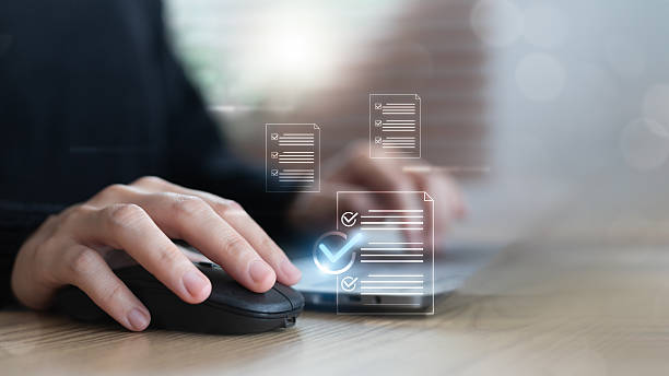 Hand using a mouse and a laptop with virtual documents and check marks. Concept of digital document approval, online checklist, data verification, and business workflow.