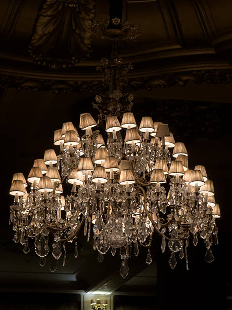 Elegant multi-tier crystal chandelier adorned with small fabric lampshades casts a soft, ambient light in a lavish classical ballroom, evoking sophistication and opulence.
