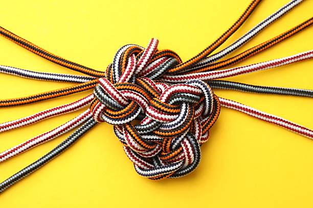 Braided colorful ropes on yellow background, top view. Unity concept