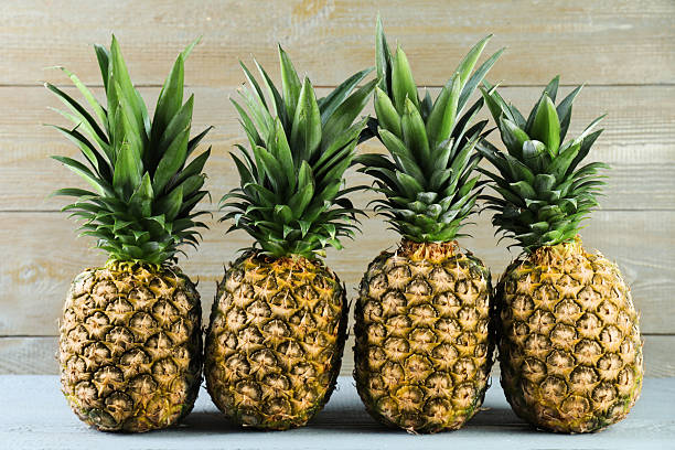 istock Fresh ripe pineapples on grey wooden table 2230793070