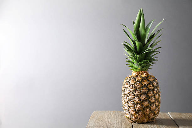 istock Fresh ripe pineapple on wooden table against light grey background. Space for text 2230793126