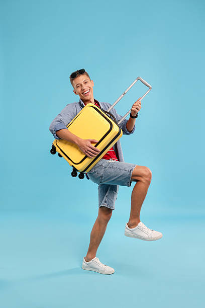 istock Happy traveller with suitcase on light blue background 2230793688