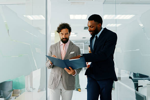 istock Two businessmen reviewing documents and discussing business matters in a modern office environment 2230793710