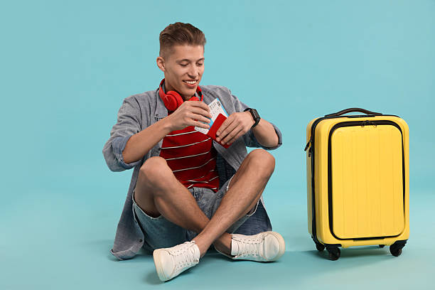 istock Happy traveller with suitcase, passport and ticket on light blue background 2230793789