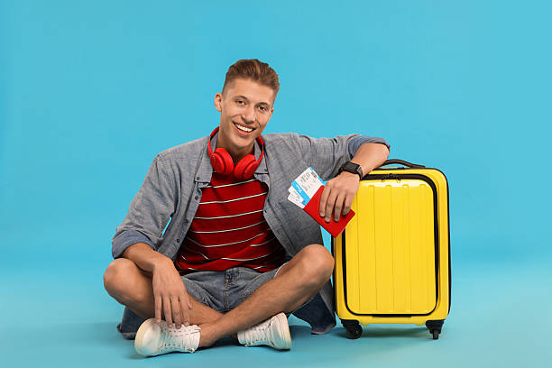 istock Happy traveller with suitcase, passport and tickets on light blue background 2230794114