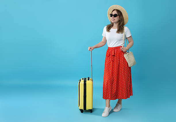 istock Happy traveller in sunglasses with suitcase on light blue background, space for text 2230794153
