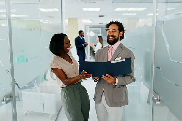 istock Multi-ethnic business partners reviewing documents and laughing in modern office 2230794411