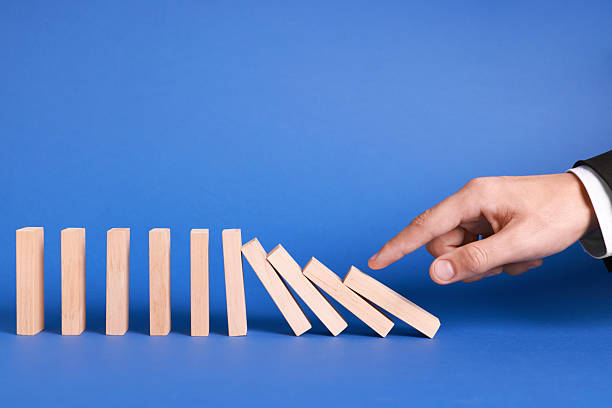 istock Domino effect. Man pushing wooden blocks on blue background, closeup 2230798671