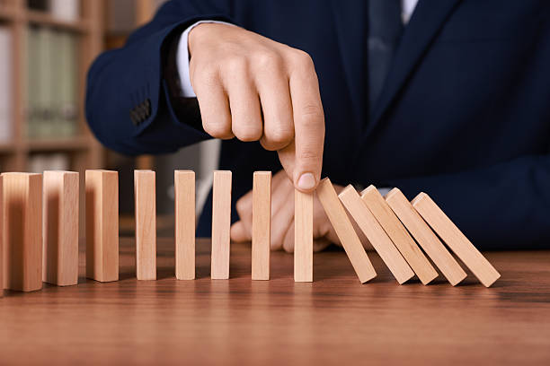 istock Domino effect. Man pushing wooden blocks at table, closeup 2230798963