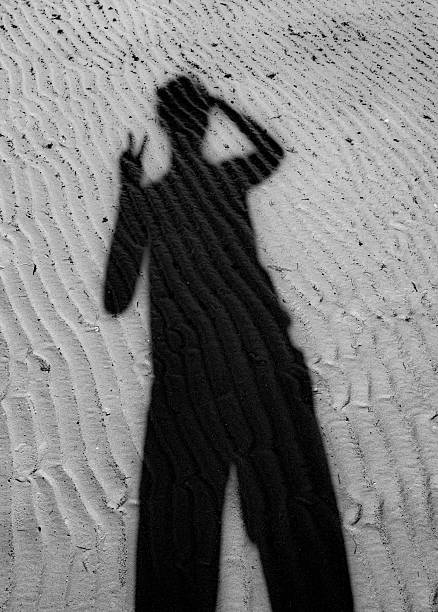 istock Abstract shadow of a person on a textured sand with hands gesturing 2230802837